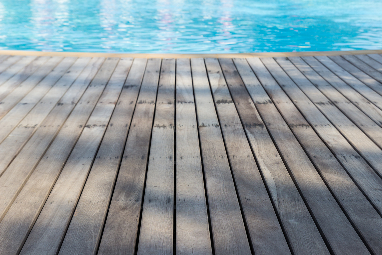 Une piscine avec une plage en bois